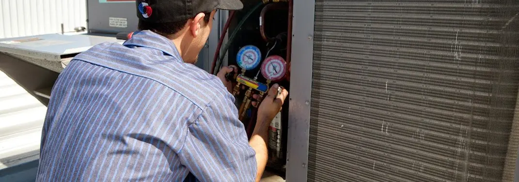 HVAC technician servicing a condenser unit in South Lakes